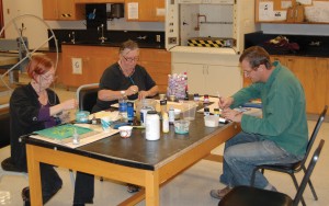 Whatcom staff members Catherine Chambers (middle), and Rob Beishline (right), work on art flags at a Whatcom Vet Art meeting.