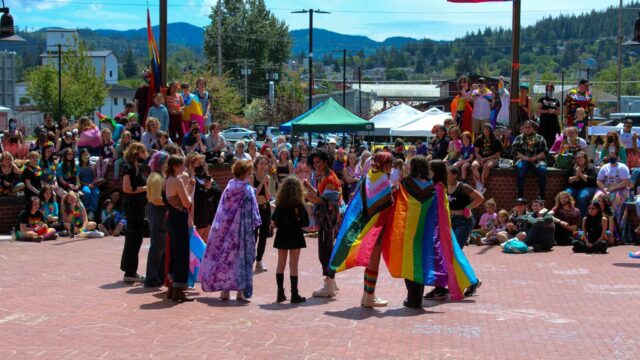 Kids gather at Pride event displaying flags