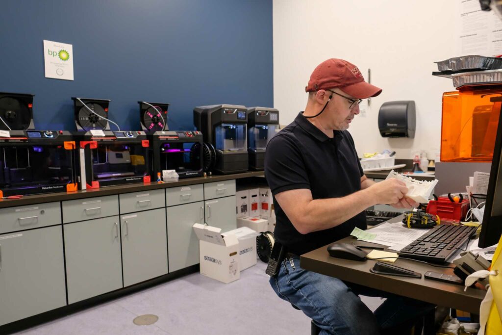 Russ Nelson, Multi-Media Services Manager Russ Nelson, who also supervises the makerspace, clears supports from a 3D printed model in the 3D printer studio in the Media Center.
